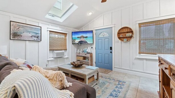 A spacious living room with a large TV, a blue door, and a ceiling fan. - Margate Home w/ Large Outdoor Kitchen (Margate City)