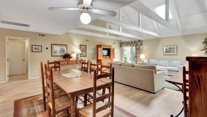 A spacious living room with a wooden dining table, a sofa, and a ceiling fan. - Turtle's Tide - Spacious Villa in Queens Grant with Private Patio by RedAwning (Hilton Head Island)