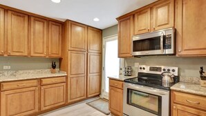 A kitchen with wooden cabinets, a stainless steel microwave, a stove, and granite countertops. - Turtle's Tide - Spacious Villa in Queens Grant with Private Patio by RedAwning (Hilton Head Island)