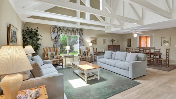 A spacious living room with a high ceiling, a large window, and a dining area. - Turtle's Tide - Spacious Villa in Queens Grant with Private Patio by RedAwning (Hilton Head Island)
