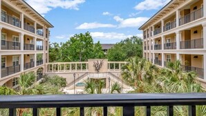 A hotel with multiple balconies, a central courtyard with a fountain, and surrounding greenery. - Shorenugh - Bright Villa with Rooftop Pool Next to Coligny Plaza by RedAwning (Hilton Head Island)