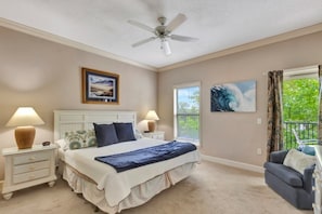 A bedroom with a bed, nightstands, a ceiling fan, a window with a view, and a balcony.