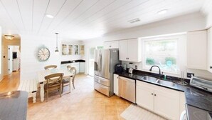Een moderne keuken met witte kasten, een roestvrijstalen koelkast en een zwart aanrecht.