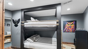 A bunk bed with a headboard, a small bedside table, and a wall-mounted shelf. - Night Owl 3 Bedroom Cabin by RedAwning (Gatlinburg)