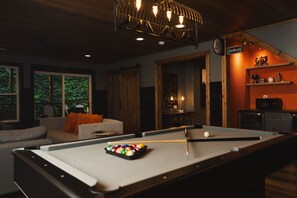 A pool table with balls, a sofa, and a bar area with a sign. - Night Owl 3 Bedroom Cabin by RedAwning (Gatlinburg)