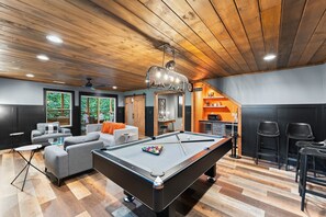 A modern living room with a pool table, grey sofas, and a ceiling fan. - Night Owl 3 Bedroom Cabin by RedAwning (Gatlinburg)