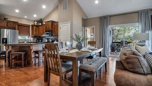 A spacious kitchen with wooden cabinets, a dining area with a table set for four, and a cozy living room with a sofa and a large window. - BEAUTIFUL Home Close to Branson Activities! (Hollister)
