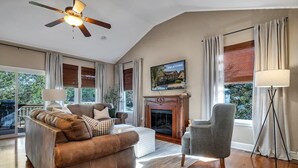 A living room with a fireplace, a sofa, a chair, and a television. - BEAUTIFUL Home Close to Branson Activities! (Hollister)