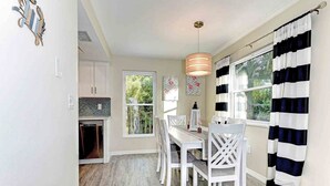 A dining area with a white table and chairs, a pendant light, and a view of the outdoors through large windows. - Sugaree -  2bedroom Private Pool Property in Holmes Beach (Holmes Beach)