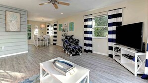 A spacious living room with a ceiling fan, a TV on a white stand, and a dining area with a table and chairs. - Sugaree -  2bedroom Private Pool Property in Holmes Beach (Holmes Beach)