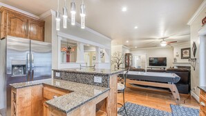 A modern kitchen with granite countertops, stainless steel appliances, and pendant lighting.
