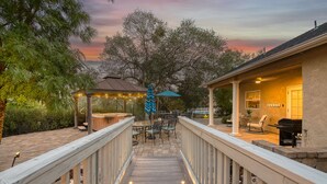 A wooden deck with outdoor seating, a gazebo, and a barbecue area.