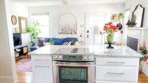 A modern kitchen with a central island, built-in oven, and white cabinetry. - The Haymount Eclectic by Haymount Homes (Fayetteville)