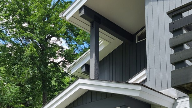 Een tweelaags huis met een overdekte veranda, een garage en een keurig onderhouden tuin.