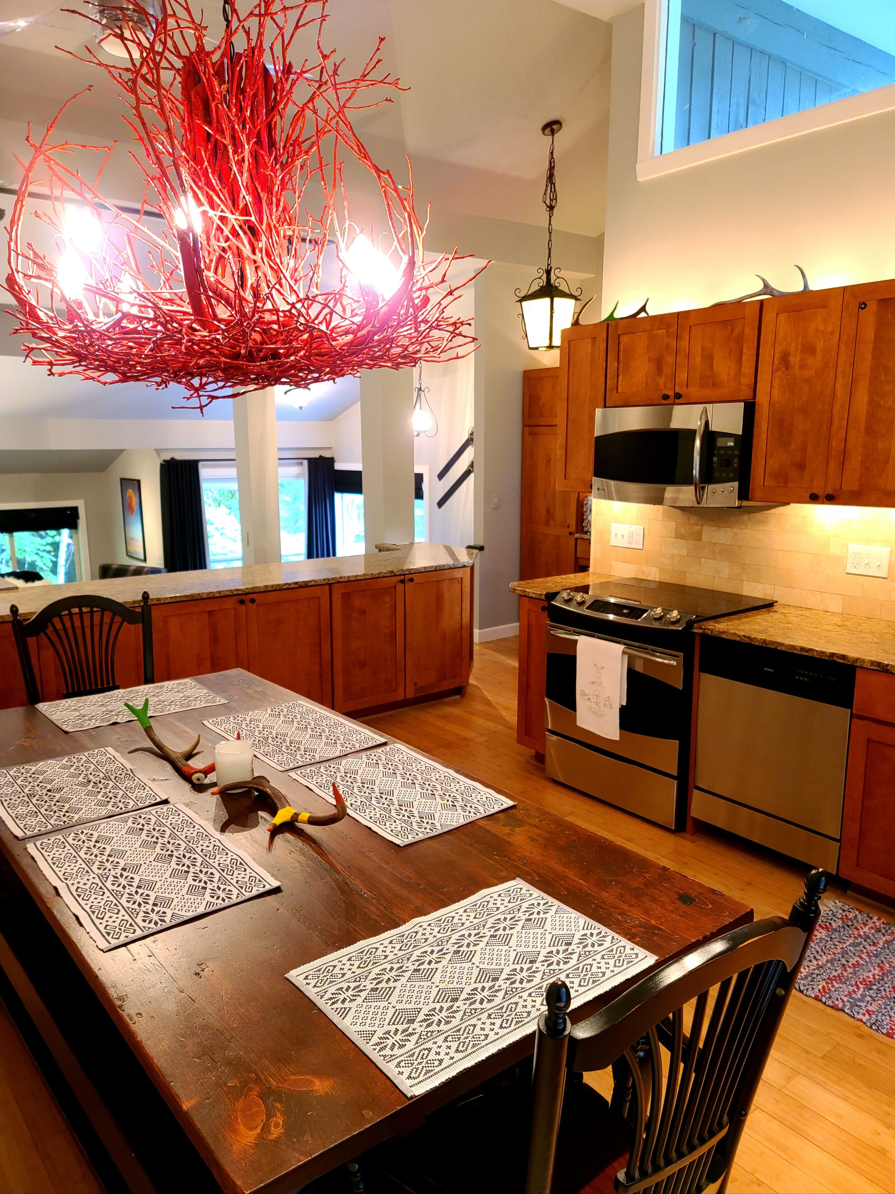 A modern kitchen with wooden cabinets, stainless steel appliances, and a dining area with a wooden table and placemats.