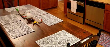 A modern kitchen with wooden cabinets, stainless steel appliances, and a dining area with a wooden table and placemats.