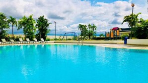 Una piscina con sillones de descanso y palmeras.