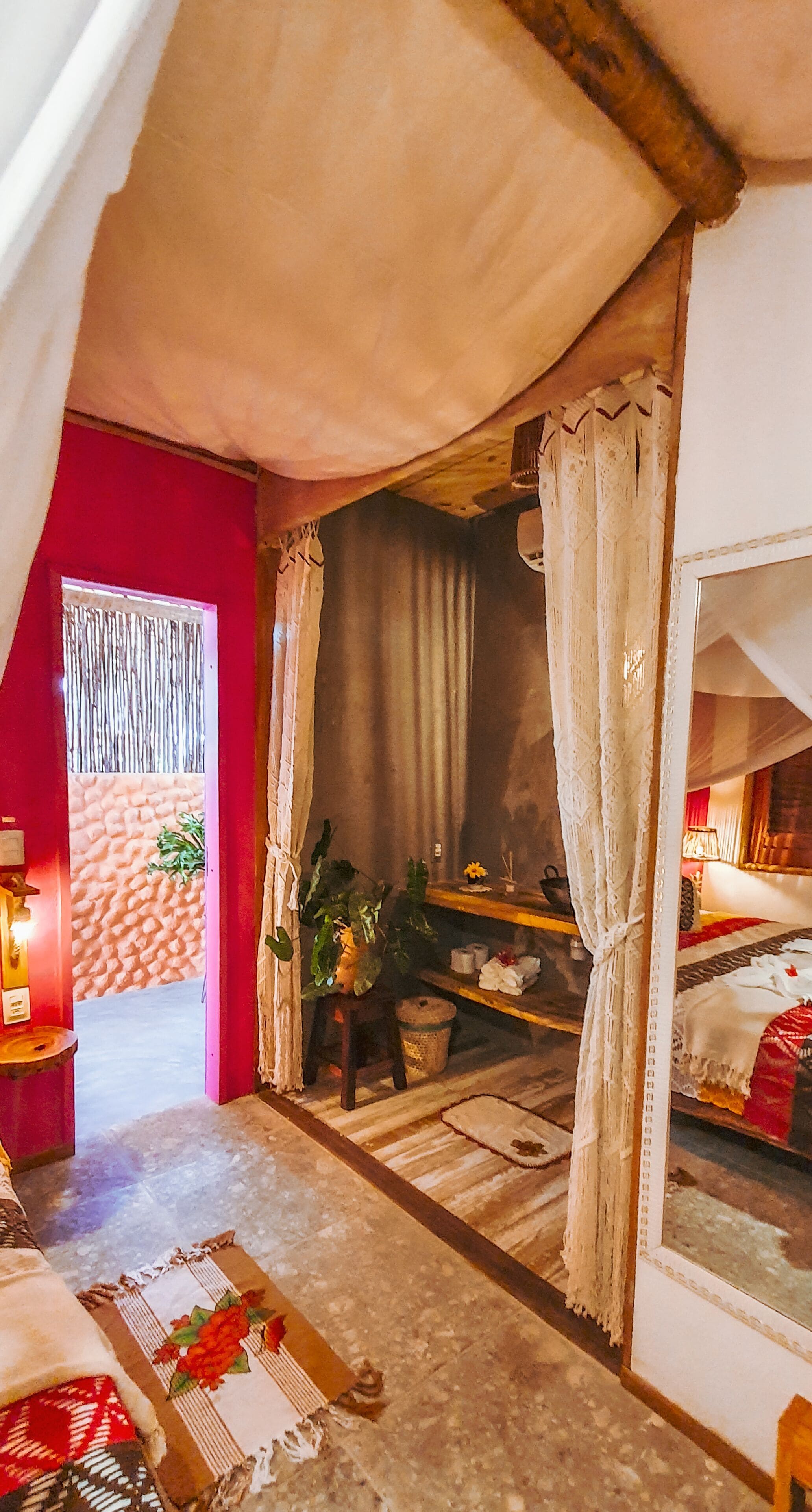 A cozy room with a bed, a small table with a lamp, and a window with curtains.