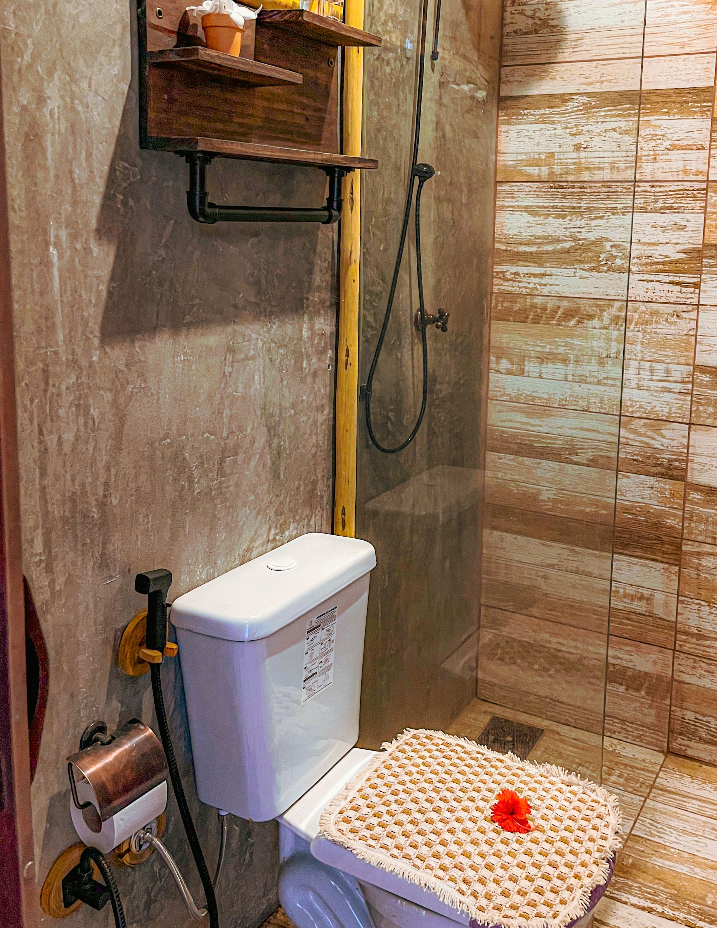 A bathroom with a shower, toilet, and a shelf with toiletries.
