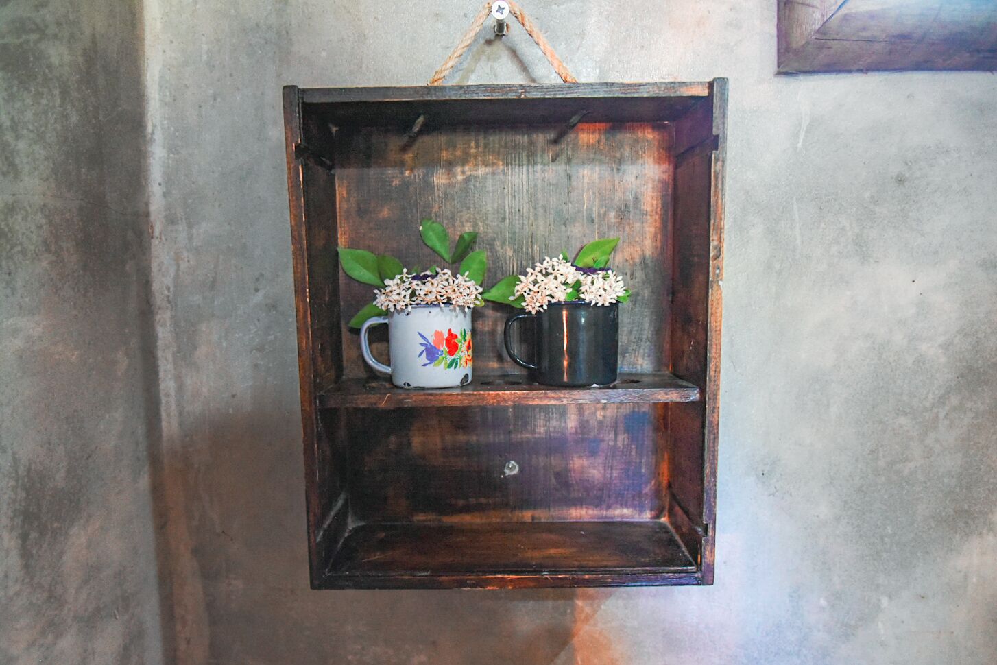 Una estantería rústica de madera con dos tazas de cerámica, cada una con una pequeña planta.