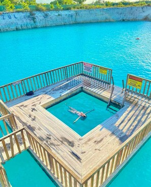 A wooden deck with a swimming pool, surrounded by a white wall and a wooden railing. - Pousada Quinta da Lagoa Azul (Cruz)