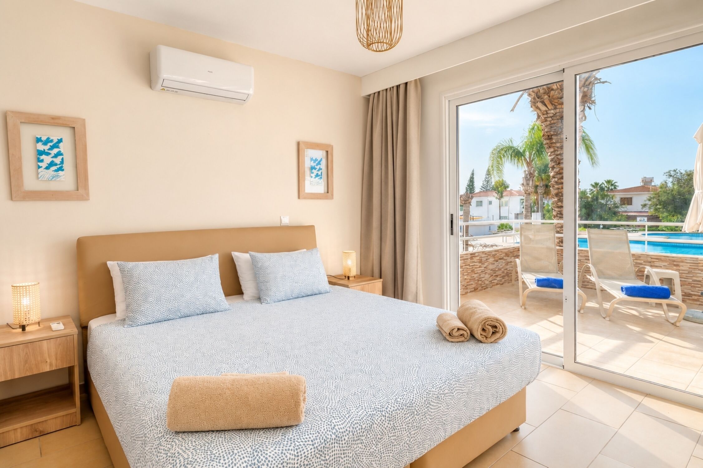 A bedroom with a large bed, a sliding glass door to a balcony, and a pool view.