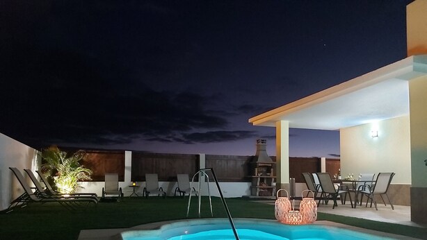 Un jardin avec une piscine, des chaises longues, un espace barbecue et une table à manger.