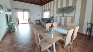 Un vaste espace de vie comprenant une table à manger, des chaises, un canapé et une grande fenêtre.