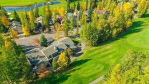 Ett flygbildsbild av ett bostadsområde med hus, en golfbana och en damm.