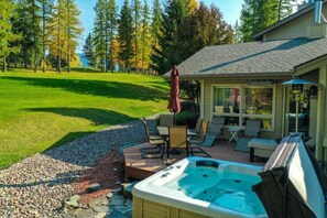 Ein Whirlpool in einem Garten mit Terrassenbereich, umgeben von Rasen und Bäumen.