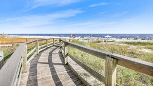 A wooden boardwalk leading to a beach with clear skies.