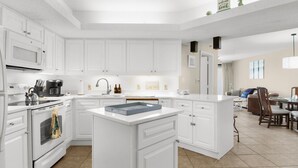 A modern kitchen with white cabinetry, a central island, and a dining area with a table and chairs.