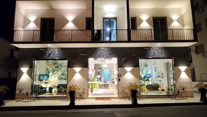 A hotel with a two-story facade, large glass windows, and a balcony with wooden railings. - Hotel Tea Praia  (Praia a Mare)