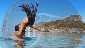 A woman in a black swimsuit in a clear blue pool with a rocky landscape in the background. - Hotel Tea Praia  (Praia a Mare)