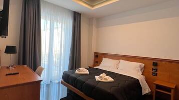 Ein modernes Hotelzimmer mit Bett, Nachttisch und Schreibtisch mit Lampe.