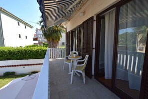 Ein Balkon mit Tisch und Stühlen, eine Palme und ein Gebäude im Hintergrund.