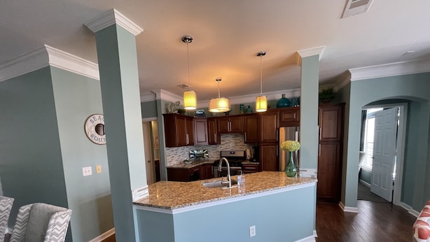 A modern kitchen with granite countertops, wooden cabinets, and pendant lighting. - Biloxi border, huge King size Condo (Gulfport)