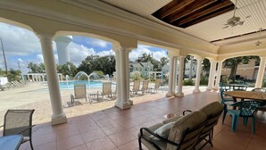 A covered outdoor area with a pool, lounge chairs, and a dining table. - Biloxi border, huge King size Condo (Gulfport)