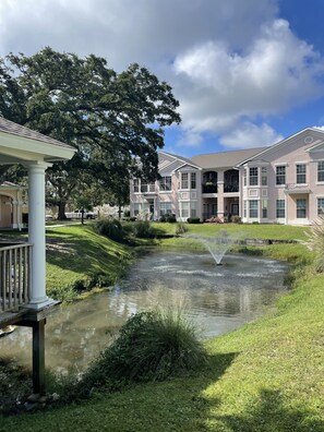 A residential area with a pond, a gazebo, and multi-story buildings with balconies. - Biloxi border, huge King size Condo (Gulfport)