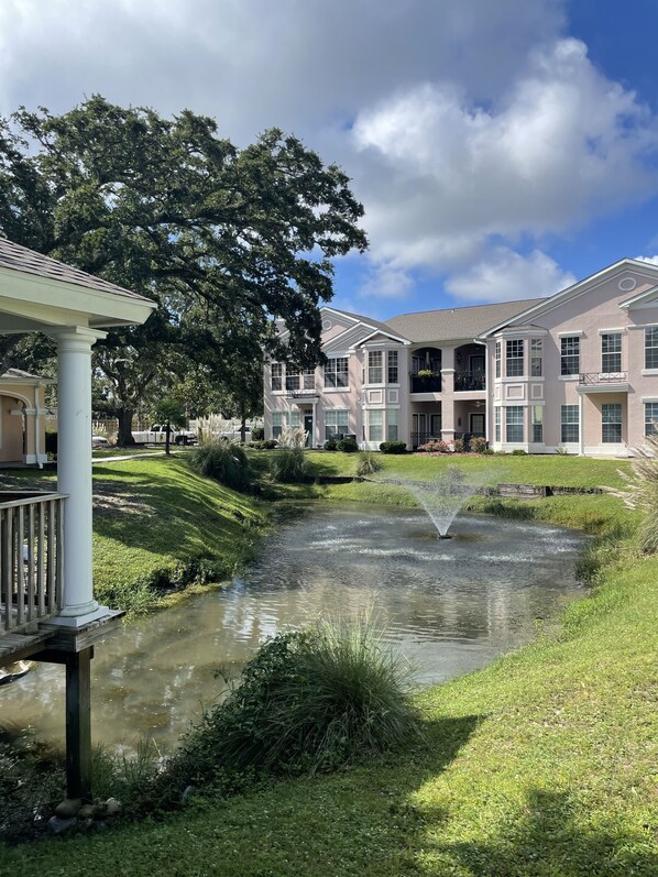 A residential area with a pond, a gazebo, and multi-story buildings with balconies. - Biloxi border, huge King size Condo (Gulfport)