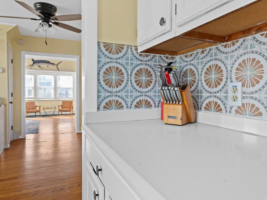 A kitchen with a white countertop, a ceiling fan, and a backsplash with a circular pattern.