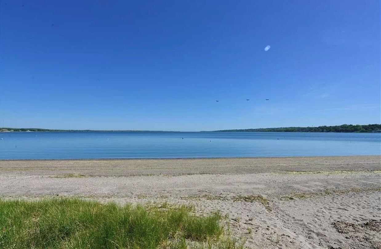 Ein Strand mit klarem Himmel und ruhiger Wasserfläche.
