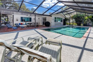 An outdoor swimming pool with lounge chairs and a covered patio area. - Pelican House · Game Room, Pool, 5 min to Beach (Tarpon Springs)