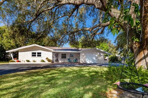 A single-story house with a front porch, a garage, and a well-maintained lawn. - Pelican House · Game Room, Pool, 5 min to Beach (Tarpon Springs)