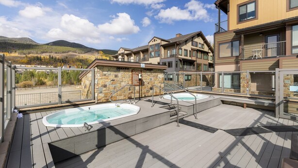 Terraza en la azotea con dos jacuzzis, muros de piedra y vistas a las montañas.