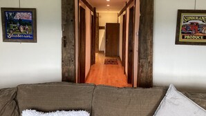 Un passadís amb bigues de fusta, un sofà amb un coixí blanc i dos quadres emmarcats a les parets.