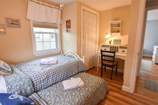 A bedroom with two beds, a desk, and a chair.