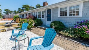 A motel with a covered outdoor seating area, two blue Adirondack chairs, and a brick pathway. - 1/2 Mile to Nantucket Sound Beaches! (Dennis Port)