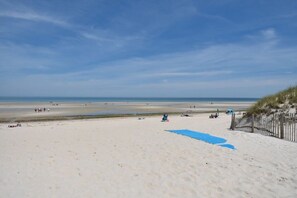 A beach with a sandy shore, a wooden fence, and a clear sky.