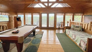 A wooden cabin interior with a pool table, a sofa, and a chair. - Mountain View Cabin Near Pigeon Forge +Hot Tub + Game Room (Sevierville)